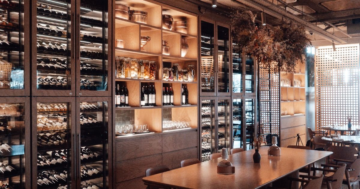Mur à vin sur-mesure intégré avec armoires vitrées de grande capacité dans une salle de restaurant