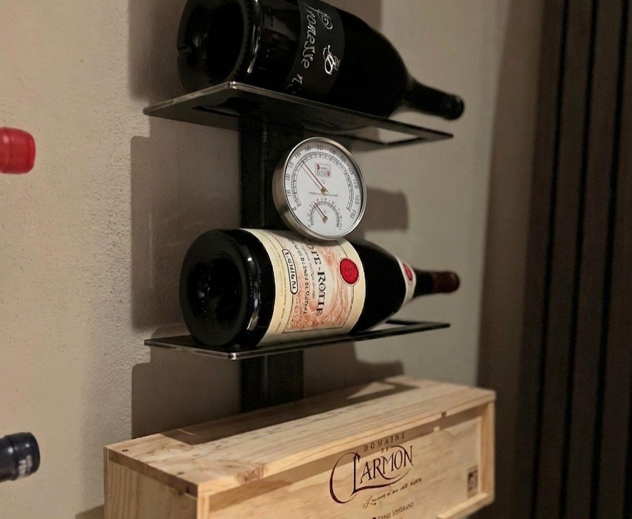 Thermomètre et hygromètre disposés près d'une étagère à vin murale pour surveiller température et humidité de la cave