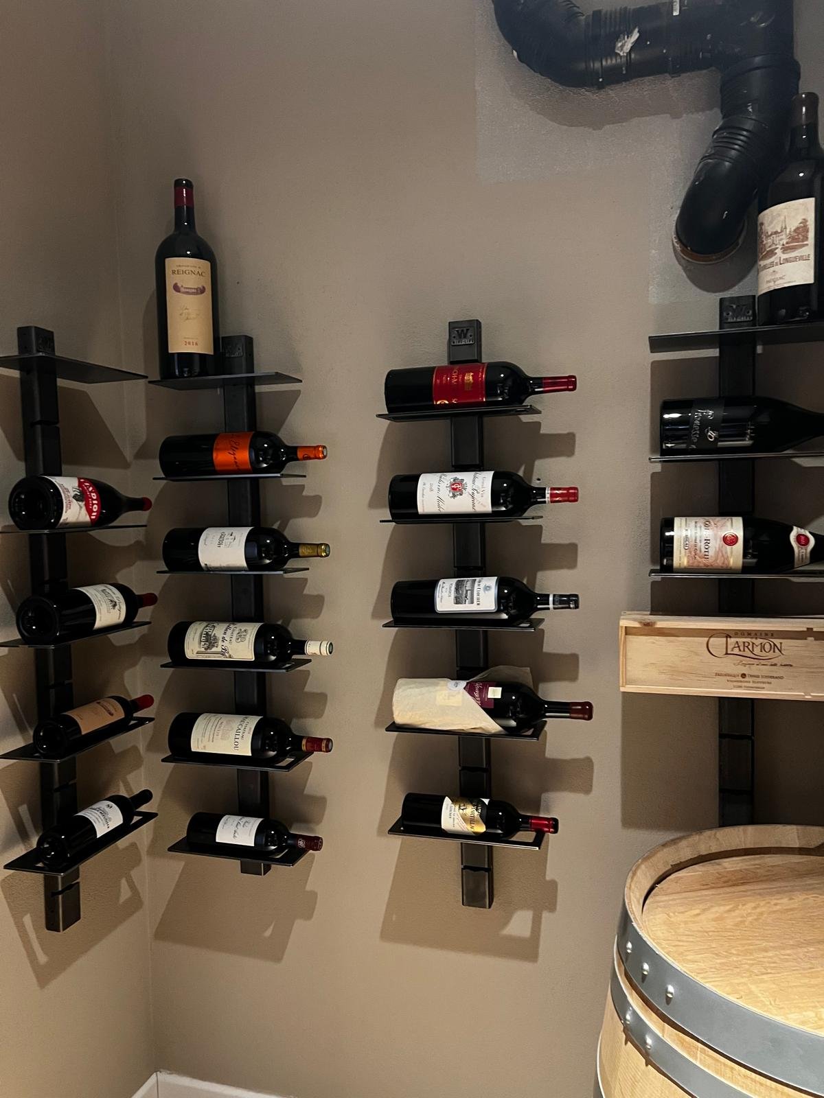 Mur de cave équipé de plusieurs étagères murales modulables Wine Line en acier juxtaposées, bouteilles couchées étiquette visible, dont un magnum
