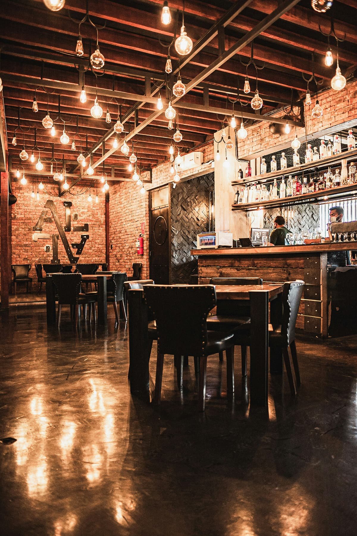 Edison bulb pendant light hanging above an industrial bar counter, casting a warm, soft glow