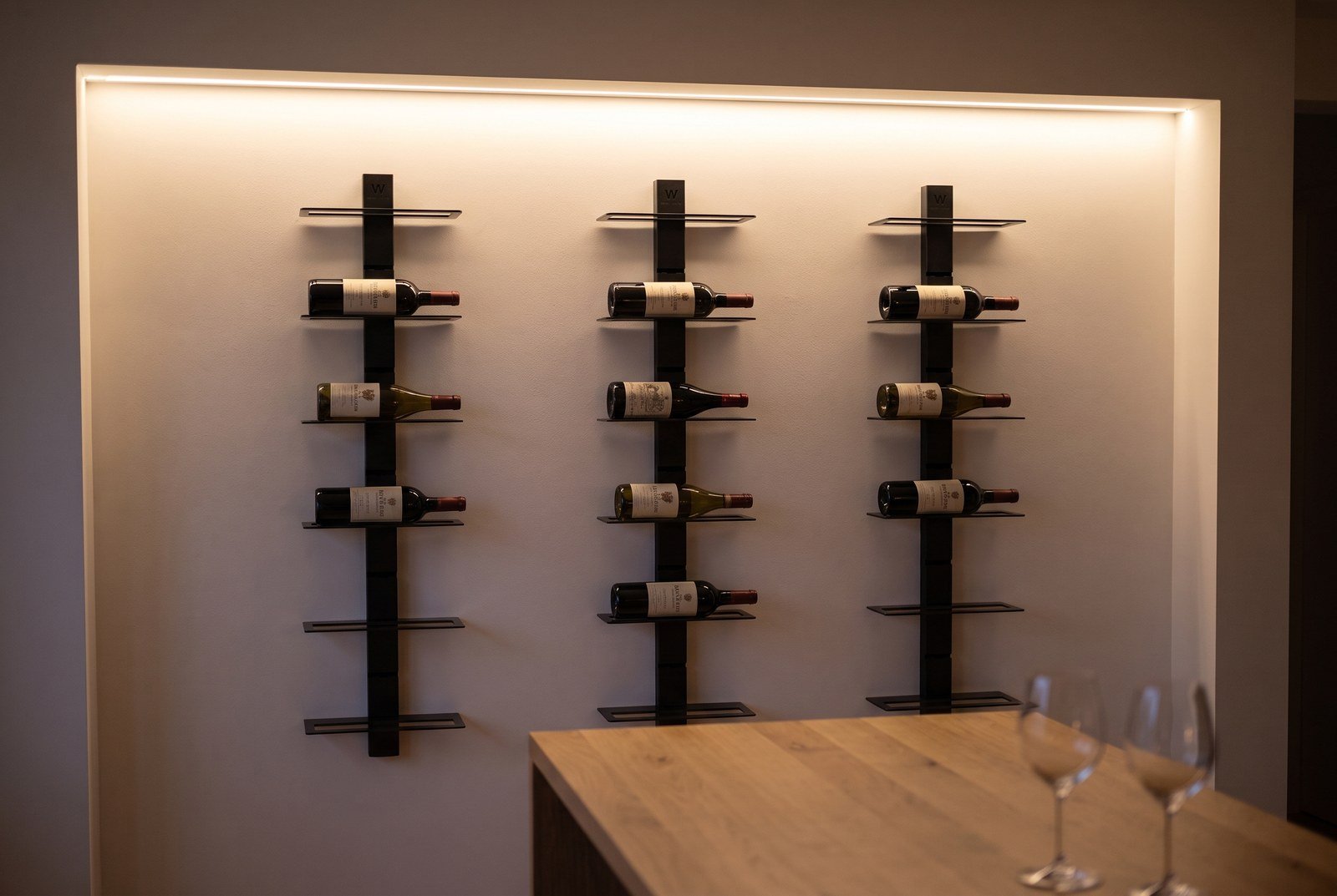Bandeau LED rasant éclairant les étiquettes d'un mur de bouteilles dans une ambiance de soirée