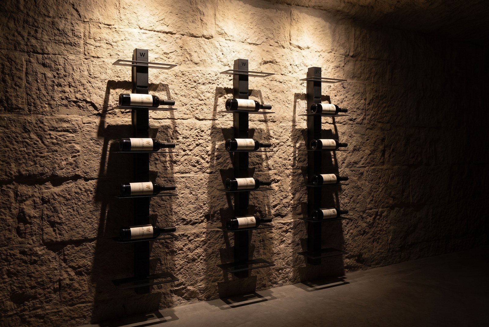 Mur à vin éclairé en lumière LED rasante chaude, le reste de la pièce dans la pénombre