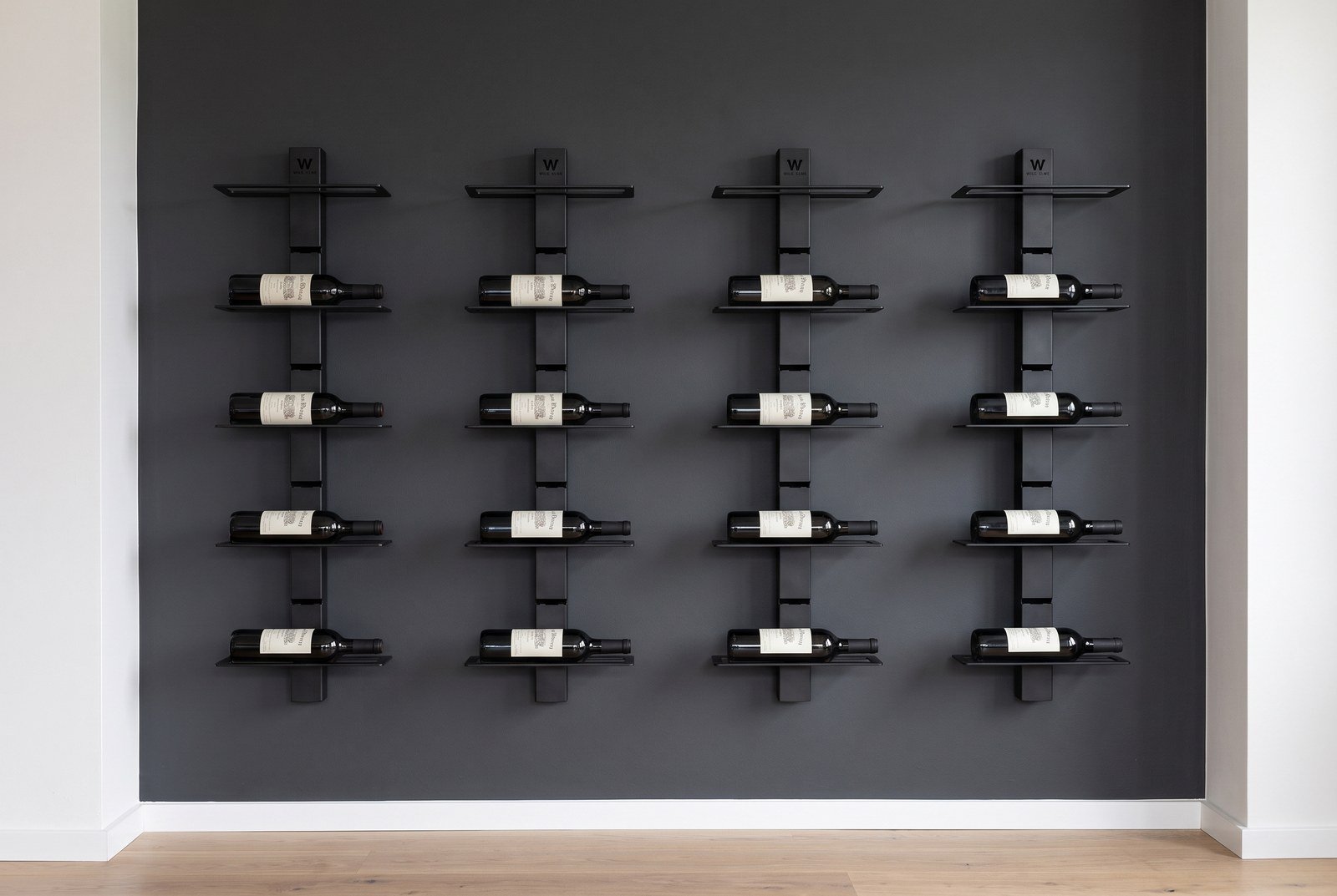 Mur à vin composé de quatre colonnes en acier laqué noir, bouteilles couchées étiquettes visibles