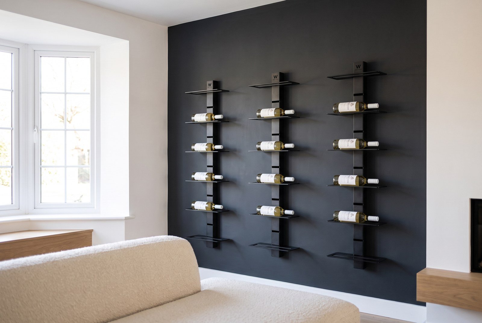 Mur à vin dans un salon contemporain, colonnes acier noir sur fond de peinture mate sombre