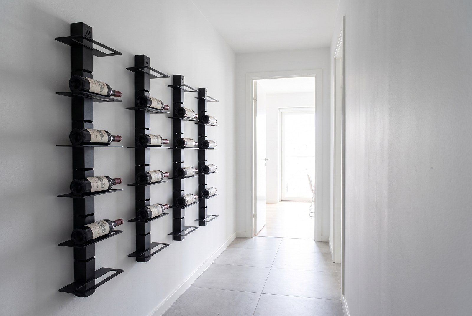 Mur de bouteilles installé dans un couloir étroit, étiquettes tournées vers le passage