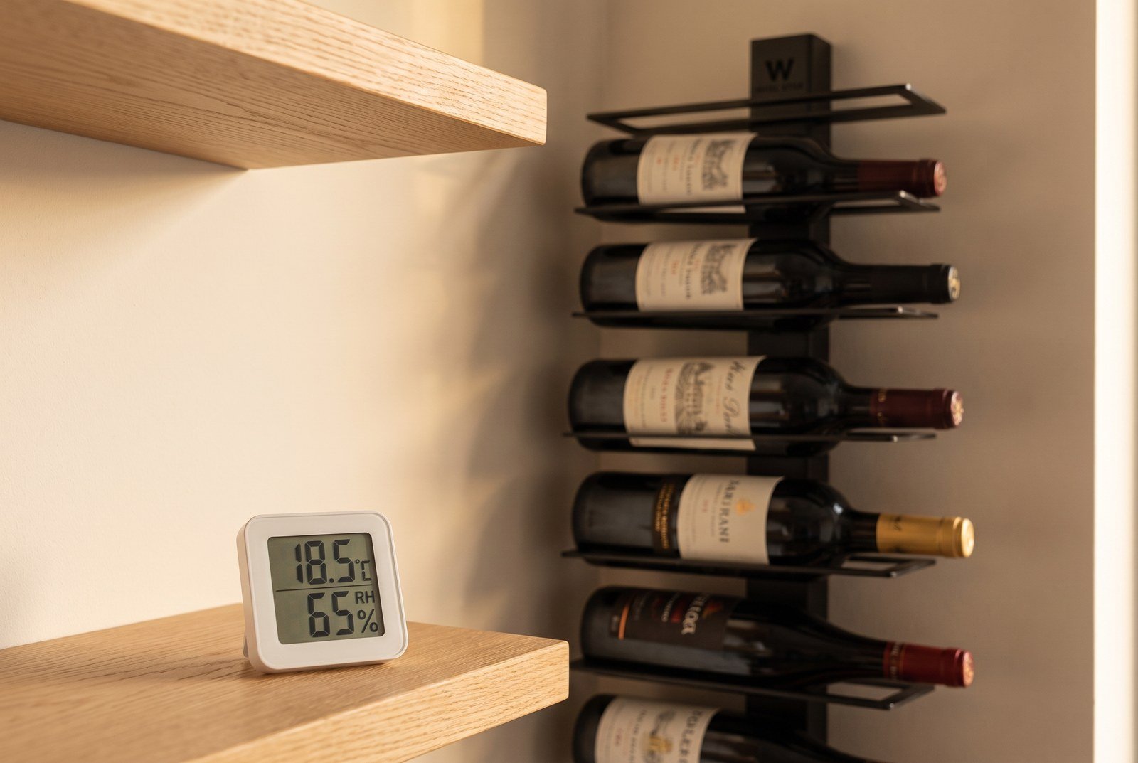 Thermomètre-hygromètre posé devant un mur de bouteilles pour contrôler la température du coin bar