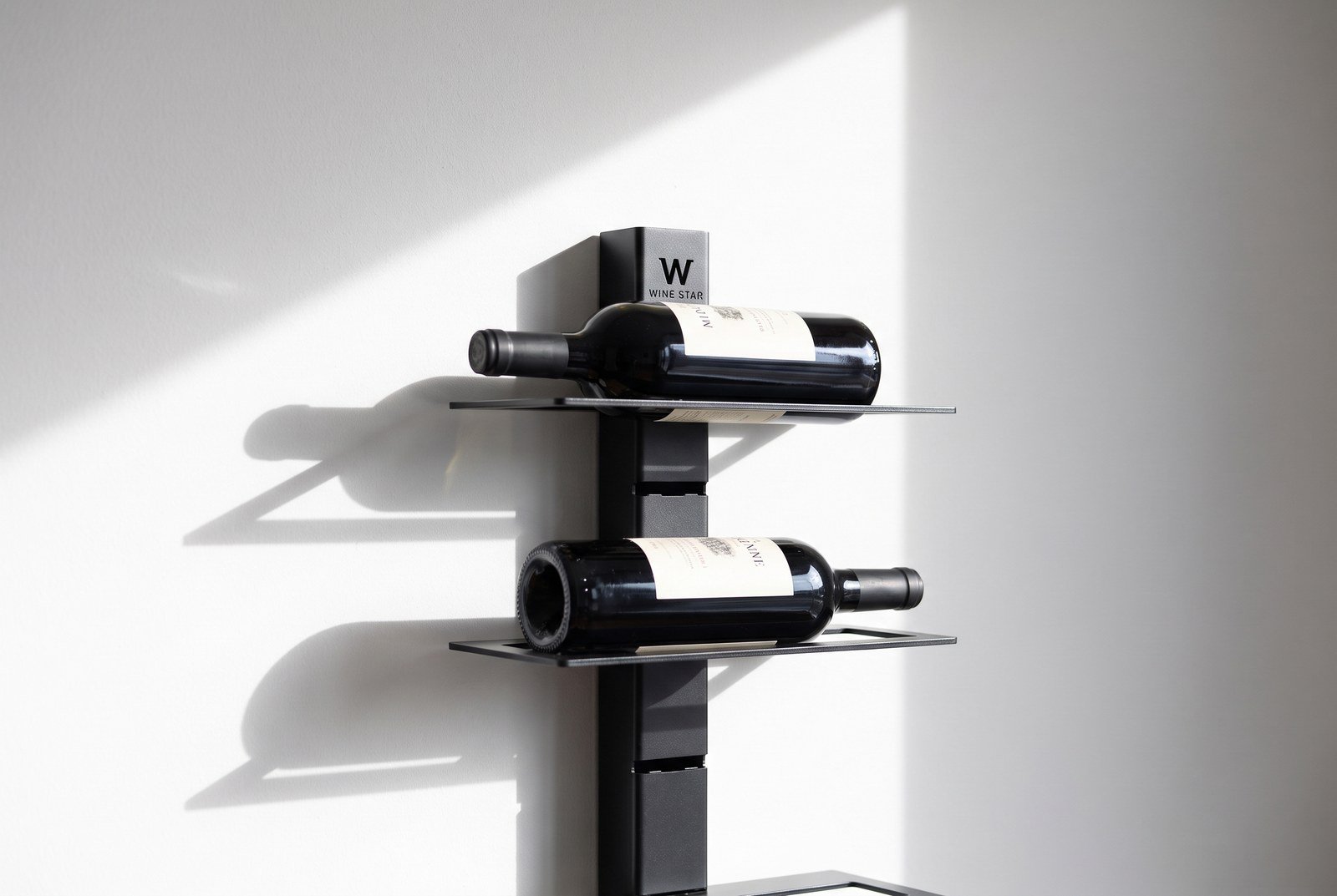 Close-up shot of the top mounting bracket of a steel wall-mounted bottle rack loaded with bottles