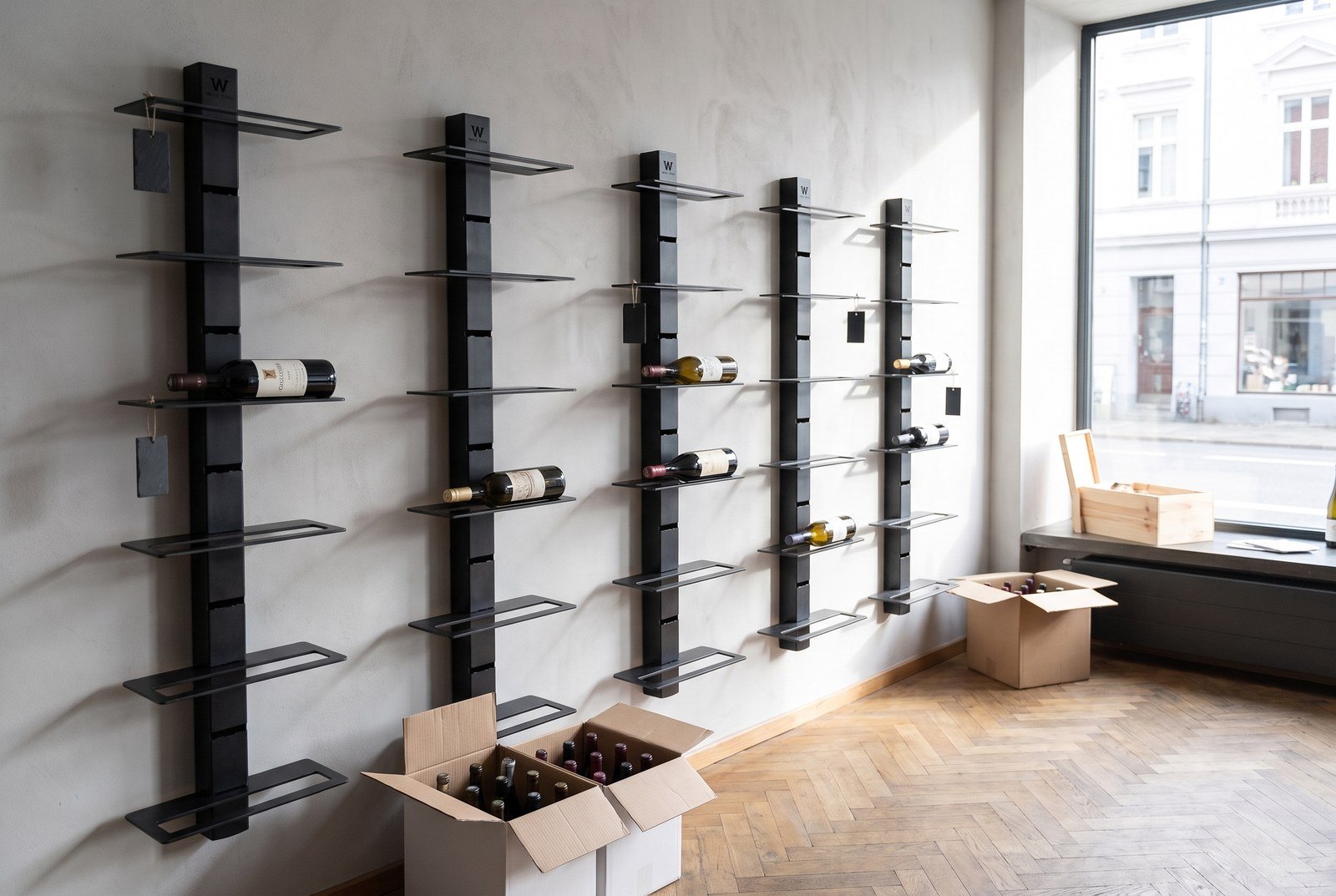 Mur de vente d'un caviste en cours de réorganisation, tablettes acier partiellement chargées