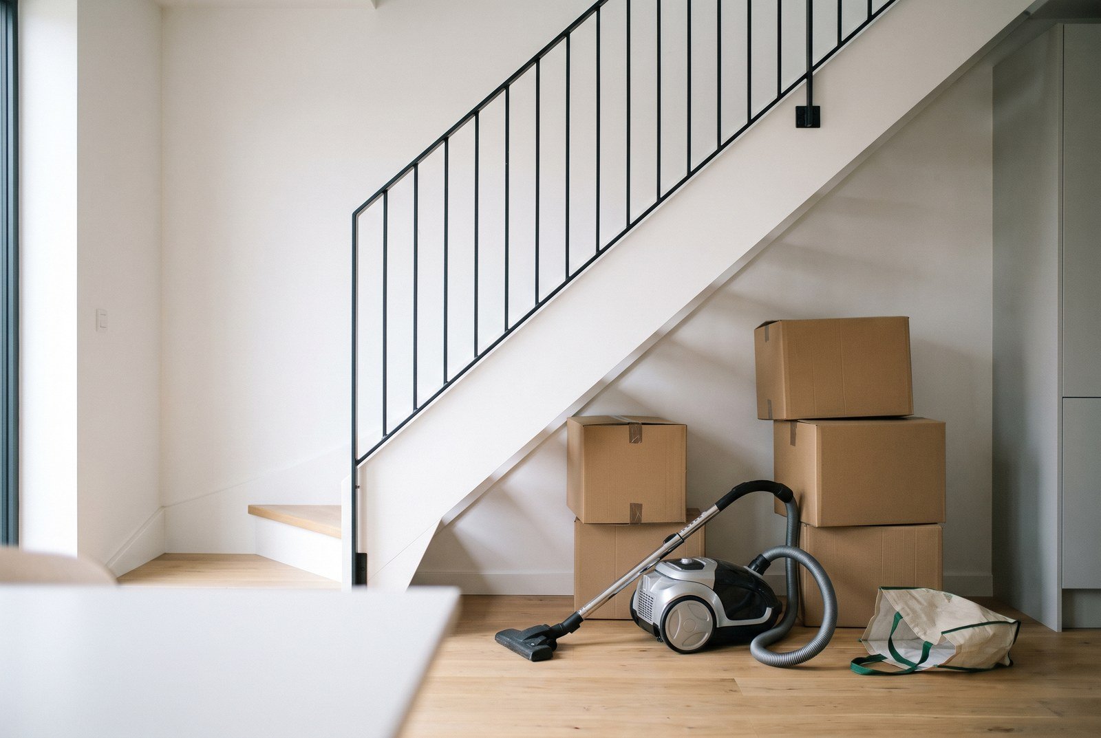 The space under the stairs, cluttered with boxes and a vacuum cleaner, before the renovation