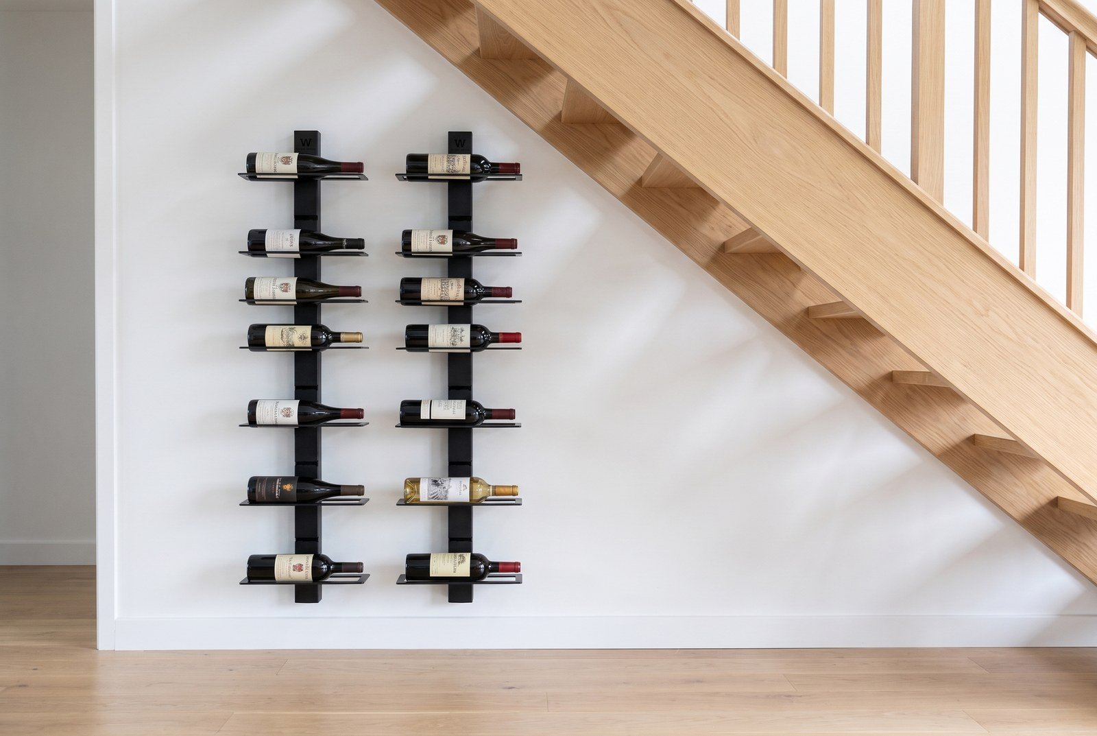 Two wine storage units mounted beneath the upper section of a staircase; the rest of the wall is bare
